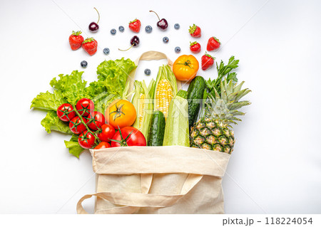 Grocery shopping. Different fresh fruit and vegetables in a textile shopper bag on white background, healthy food from supermarket or delivery concept. Grocery shopping. Different fresh fruit and vegetables in a textile shopper bag on white background, healthy food from supermarket or delivery concept. 118224054