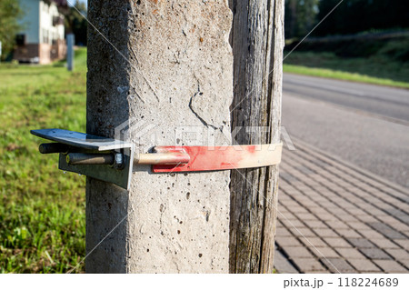 Close-up of wooden log attached to a concrete post with a metal turnbuckle 118224689