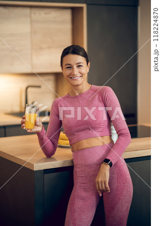 Sporty smiling young woman drinking orange juice during home workout 118224870