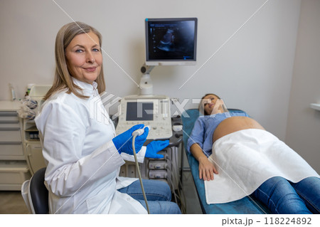 Pregnant woman lying on a couch in clinic while ultrasonography Pregnant woman lying on a couch in clinic while ultrasonography 118224892