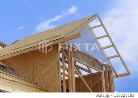 Installation of plywood on wooden roofing trusses at under construction house assembled roof 118225182
