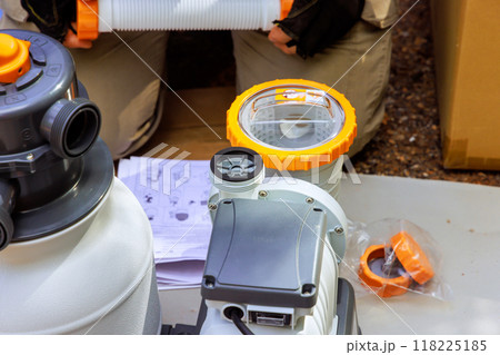 Maintenance worker assembles sand filter system tank cleaning equipment for swimming pool 118225185