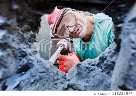 Builder pounding chiseling into tough concrete with rotary hammer. Builder pounding chiseling into tough concrete with rotary hammer. 118225974