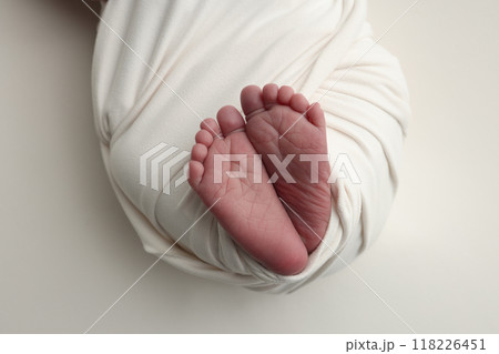 The tiny foot of a newborn. Soft feet of a newborn in a white blanket. Close up of toes, heels and feet of a newborn baby. Studio Macro photography. Woman's happiness. The tiny foot of a newborn. Soft feet of a newborn in a white blanket. Close up of toes, heels and feet of a newborn baby. Studio Macro photography. Woman's happiness. 118226451