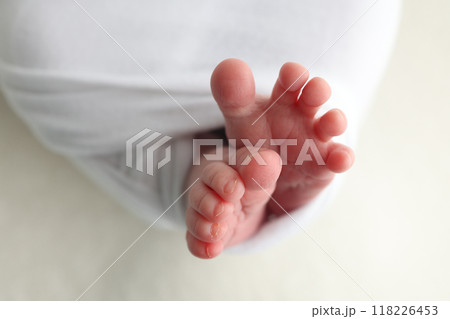 The tiny foot of a newborn. Soft feet of a newborn in a white blanket. Close up of toes, heels and feet of a newborn baby. Studio Macro photography. Woman's happiness. 118226453