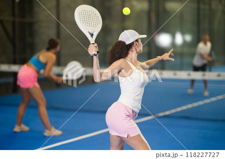 Woman playing padel on open court on summer day. Sport and active lifestyle concept 118227727