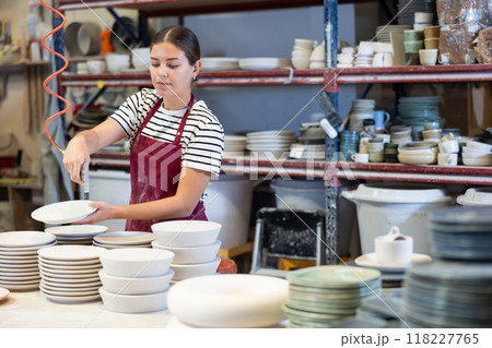 Young woman paints blanks of ceramic products Young woman paints blanks of ceramic products 118227765