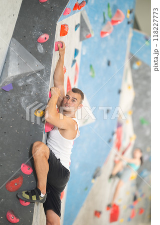 Sporty man in doing difficult wall climb in climbing gym without special climbing equipment Sporty man in doing difficult wall climb in climbing gym without special climbing equipment 118227773