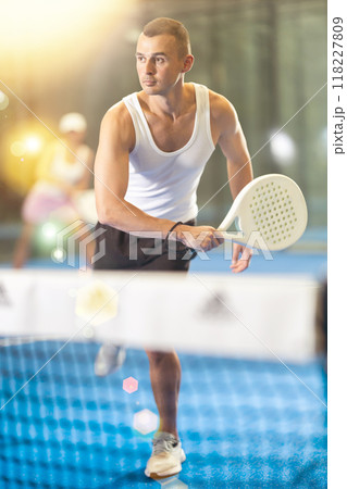 Active man with enthusiasm playing padel on tennis court 118227809