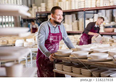 Young man moves rack with ceramic blanks 118227818