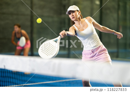 Woman playing padel on indoor court on summer day. Sport and active lifestyle concept 118227833