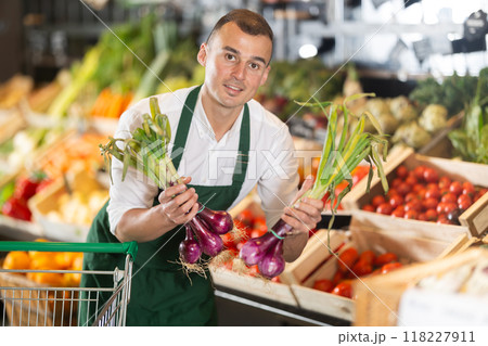 Male seller displaying bunches of purple onions at farmers market Male seller displaying bunches of purple onions at farmers market 118227911