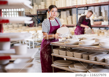 Female artisan stacking crafted ceramic plates on racks in workshop Female artisan stacking crafted ceramic plates on racks in workshop 118227970