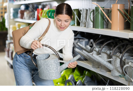 Young woman choosing watering pot in hardware store Young woman choosing watering pot in hardware store 118228090