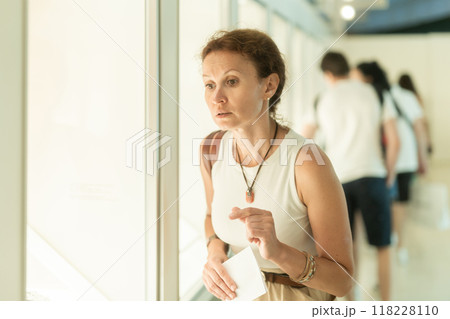 Woman looks at museum exhibit with brochure Woman looks at museum exhibit with brochure 118228110