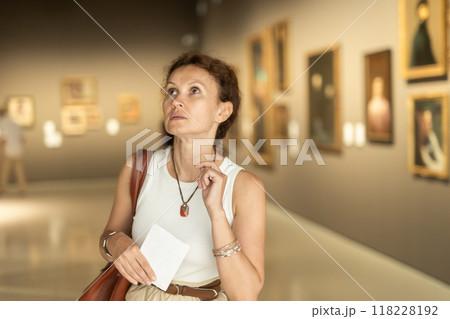 Closeup on attentive woman visiting museum and looking at exhibition of paintings Closeup on attentive woman visiting museum and looking at exhibition of paintings 118228192
