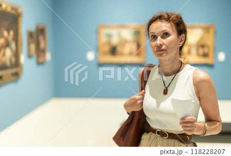 Woman viewing art gallery with brochure Woman viewing art gallery with brochure 118228207