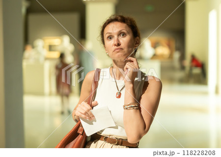 Woman looks at museum sculptures with brochure Woman looks at museum sculptures with brochure 118228208