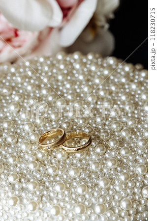 Two gold wedding rings are placed on a bed of white pearls Two gold wedding rings are placed on a bed of white pearls 118230715