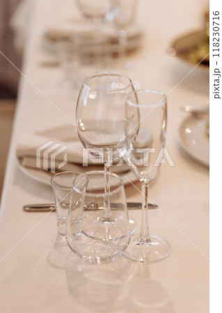 A table with a white tablecloth and a set of wine glasses and knives A table with a white tablecloth and a set of wine glasses and knives 118230716