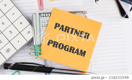 Economy and business concept. PARTNER PROGRAM on a yellow sticker on top of dollar bills 118231549
