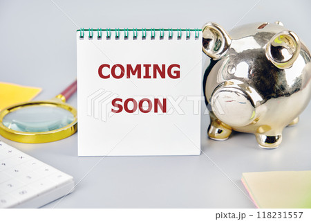 Conceptual coming soon symbol. Copy space. COMING SOON words written on a white notepad with business accessories close-up 118231557