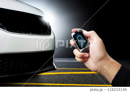 Driver hand holds keyless remote with key locked icon on display with white modern car parked Driver hand holds keyless remote with key locked icon on display with white modern car parked 118233136