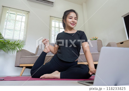 Woman practicing yoga with laptop in cozy home setting Woman practicing yoga with laptop in cozy home setting 118233825