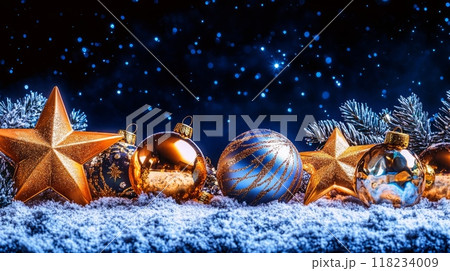 Gold and blue Christmas decorations with stars and pine branches on snowy ground under starry night sky. 118234009