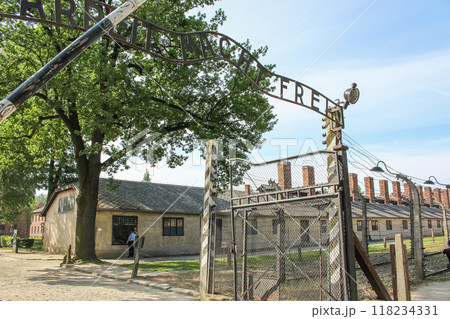 Poland, Oswiecim 06 15 2018 Gate to concentration camp Auschwitz, Oswiecim. Entrance with nazi slogan and barrack on background. Holocaust memorial. Symbol of fascism violence. Jewish genocide. Poland, Oswiecim 06 15 2018 Gate to concentration camp Auschwitz, Oswiecim. Entrance with nazi slogan and barrack on background. Holocaust memorial. Symbol of fascism violence. Jewish genocide. 118234331