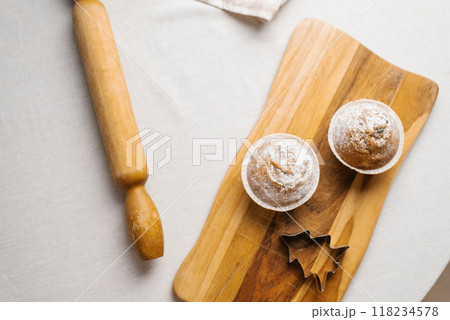 Two muffins on a wooden board with a rolling pin and a leaf cutter 118234578