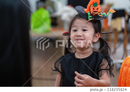 Asian toddler in Halloween attire with mother enjoying festive decor Asian toddler in Halloween attire with mother enjoying festive decor 118235824