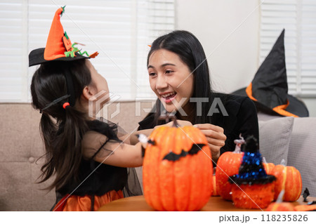 Mother and daughter sharing Halloween joy with pumpkin crafts Mother and daughter sharing Halloween joy with pumpkin crafts 118235826