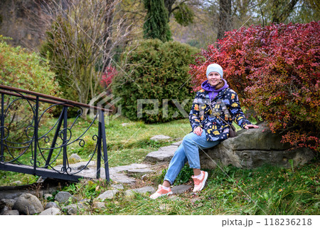 Carefree young woman in trendy vintage pants sitting on table in 118236218