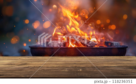 barbecue BBQ grill with flaming fire and ember charcoal on blurred background outdoors, wooden table 118236351