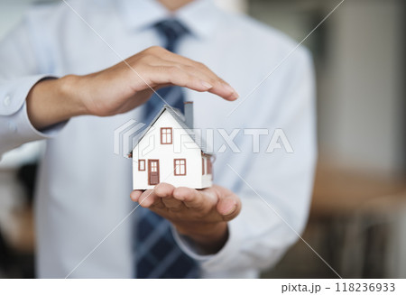 Real Estate Agent Protecting House Model Symbolizing Insurance and Homeownership 118236933
