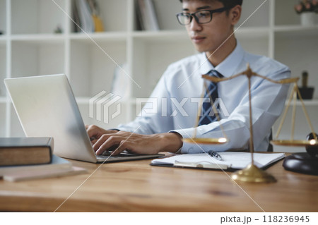 Lawyer Working on Laptop with Scales of Justice in Office 118236945