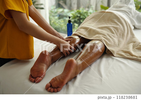 Massagist Treating Client's Leg in Spa Setting 118238681