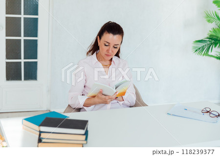 Beautiful business woman reading a book at her desk in the office 118239377