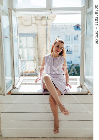 Beautiful woman of 40 years old sitting by the window on the windowsill 118239500