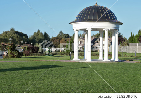White rotunda in park. Building with columns and roof for holidays. Architectural structures and recreation. Lawn background.  118239646