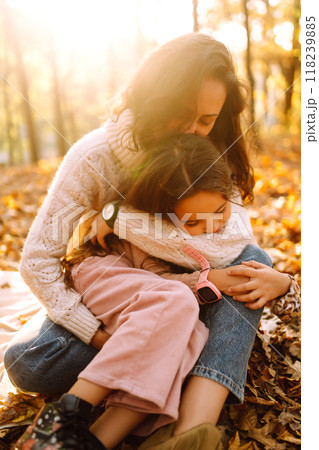 Stylish young Mother and daughter walking in the autumn forest at sunset. Family on a walk. 118239885