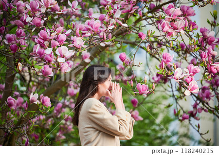 Woman allergic suffering from seasonal allergy at spring in blossoming garden at springtime. Young woman sneezing, having runny nose in front of blooming tree. Spring allergy concept Woman allergic suffering from seasonal allergy at spring in blossoming garden at springtime. Young woman sneezing, having runny nose in front of blooming tree. Spring allergy concept 118240215