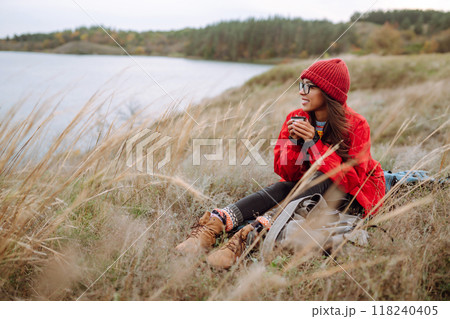 Beautiful woman drinking tea from thermos on cold autumn day. Rest, relaxation, lifestyle concept. 118240405