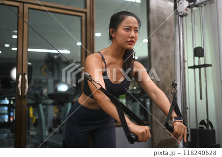 Determined athletic young woman working out in a gym, using a cable machine Determined athletic young woman working out in a gym, using a cable machine 118240628