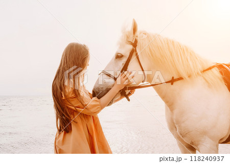 A white horse and a woman in a dress stand on a beach, with the A white horse and a woman in a dress stand on a beach, with the 118240937
