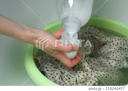 Woman is washing dress from delicate fabric by hands in basin pouring rinser. Woman is washing dress from delicate fabric by hands in basin pouring rinser. 118242457