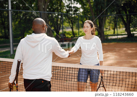 Tennis players finidhes the game. Black man and female friend giving handshake after game near net. 118243660
