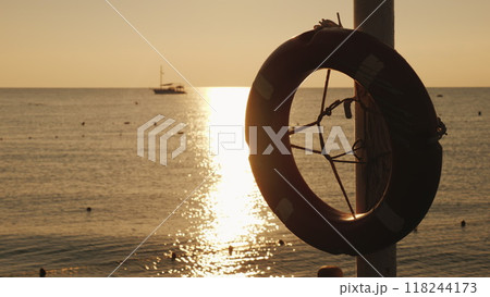 Dawn on the sea, in the foreground hangs a life ring, in the distance the ship is visible. Scenic landscape early morning 118244173