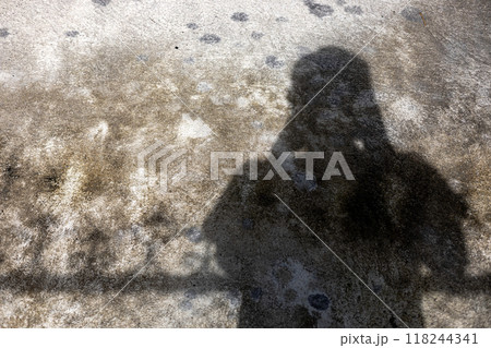 A silhouette of photographer with his equipment on the cement floor. 118244341